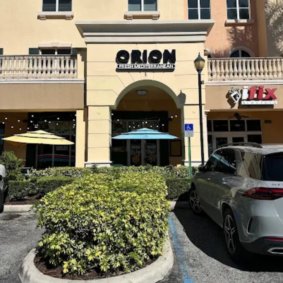 Orion Fresh Mediterranean restaurant exterior with outdoor seating, umbrellas, and a parked car.